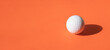 White dimple hockey ball and golf ball on orange color background. Professional sport concept