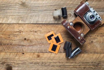 vintage photo cameras in a leather case, negatives and slides on a textured wooden table. View from above. retro style. Space for text.