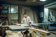© Zamrznuti tonovi - A worker is operating a cutting machine in a messy carpentry shop.
