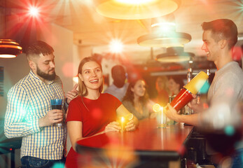 Wall Mural - Young man bartender shaking cocktail for friends, patry in nightclub