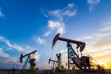 Wall Mural - in the evening, oil pumps are running, The oil pump and the beautiful sunset reflected in the water, the silhouette of the beam pumping unit in the evening.