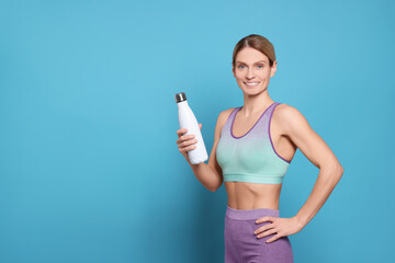 Poster - Sportswoman with thermo bottle on light blue background, space for text