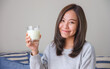 © Farknot Architect - Portrait image of a young woman holding and showing a glass of fresh milk