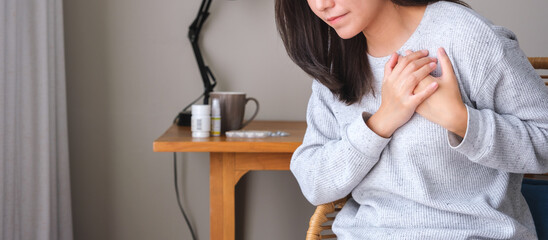 Closeup image of a woman with hands on chest, sudden heart attack, suffering from chest pain