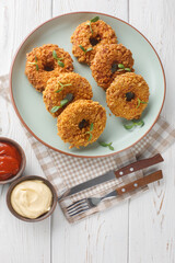 Sticker - Donug is a big chicken nugget shaped into a circle, so that it looks similar to a doughnut closeup on the plate on the table. Vertical top view from above