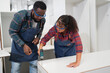 © chachamp - Asia woman and African American carpenter use working with furniture at wood factory