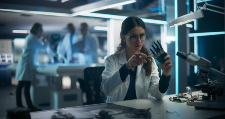Poster - Rack Focus Switching from a Female Engineer Fixing a Bionic Hand Component to Industrial Robotics Specialists in Lab Coats Working on a Mobile AI Robot in a Tech Factory Facility