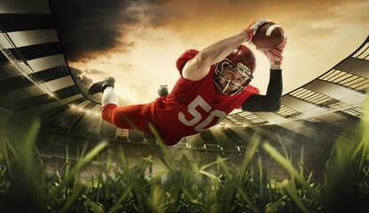 Wall Mural - American football player in sports uniform and protective equipment jumping to catch ball at 3D model sport stadium arena. Motion and action