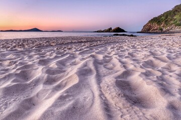 Poster - Beautiful sandy coastline with splashing waves at a pink sunset