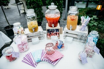 Canvas Print - Top view of the drinks dispensers and candy jars with colorful napkins on an outdoor white table