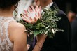 Shallow focus shot of a bride holding a bouquet with a king protea flower