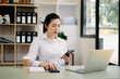 © Nuttapong punna - Young beautiful woman typing on tablet and laptop while sitting at the working wooden table office.