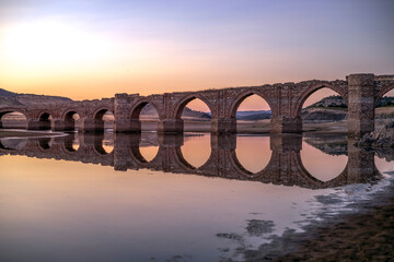 Wall Mural - La Mesta bridge of medieval construction over the Guadiana river at sunrise in the Cjara reservoir in the province of Badajoz, Spain