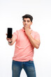 © Niks Ads - Young man standing in casual t shirt and showing smartphone screen.