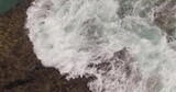 Fototapeta Natura - A picturesque view of rocks and stormy waves on the shore of a large island. Air shot