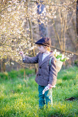 Wall Mural - Beautiful stylish toddler child, boy, playing with Easter decoration in the park, springtime