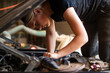 © Austockphoto - young australian tradesperson mechanic fixing car working under bonnet on engine