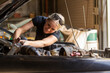 © Austockphoto - young female australian tradesperson mechanic working on car engine in auto repair garage