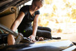 © Austockphoto - young female tradesperson mechanic fixing car engine in automotive repair garage