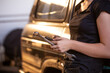 © Austockphoto - Close up shot of a woman leaning on SUV holding a mobile phone and a spanner in auto garage workshop
