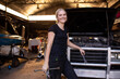 © Austockphoto - Young female aussie mechanic holding tools and leaning on a car in need of repair in workshop garage