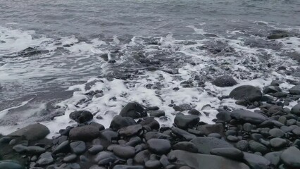 Wall Mural - Volcanic beach. Dark water and foam on the beach