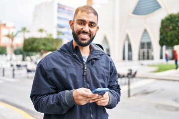 Sticker - Young hispanic man smiling confident using smartphone at park