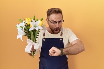 Sticker - Middle age man with beard florist shop holding flowers looking at the watch time worried, afraid of getting late