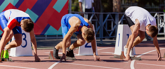 Wall Mural - male athletes ready start running 100 meters in track stadium, summer athletics championship