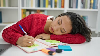 Canvas Print - Young beautiful hispanic woman student writing notes tired at library university