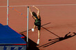 male athlete high jump in summer athletics championships, shadow jumper on red track stadium