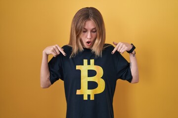 Sticker - Blonde caucasian woman wearing bitcoin t shirt pointing down with fingers showing advertisement, surprised face and open mouth