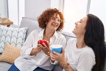 Wall Mural - Two women mother and daughter drinking coffee at home