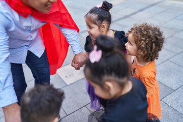 Hispanic man and group of kids wearing halloween costume dancing at street