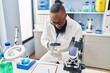 © Krakenimages.com - Young african american man wearing scientist uniform using loupe at laboratory
