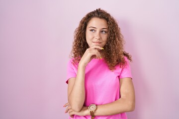 Poster - Young caucasian woman standing over pink background with hand on chin thinking about question, pensive expression. smiling and thoughtful face. doubt concept.