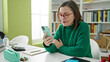 © Krakenimages.com - Mature hispanic woman with grey hair student using smartphone at library