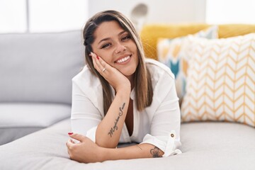 Poster - Young hispanic woman smiling confident lying on sofa at home