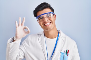 Sticker - Hispanic man working as scientist smiling positive doing ok sign with hand and fingers. successful expression.