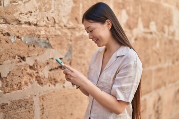 Wall Mural - Chinese woman smiling confident using smartphone at street