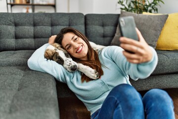 Wall Mural - Young woman hugging dog making selfie by the smartphone at home