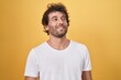 © Krakenimages.com - Young hispanic man smiling confident looking to the side over isolated yellow background