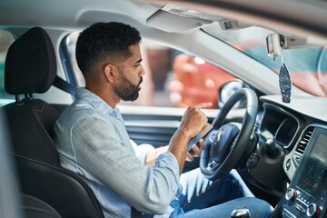 Sticker - Young arab man using smartphone sitting on car at street