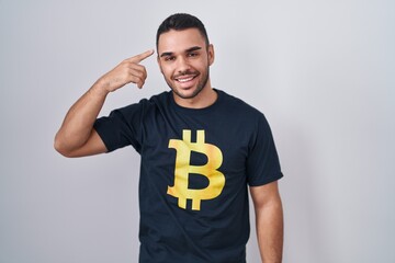 Poster - Young hispanic man wearing bitcoin t shirt smiling pointing to head with one finger, great idea or thought, good memory