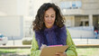 © Krakenimages.com - Middle age hispanic woman smiling confident writing on clipboard at park