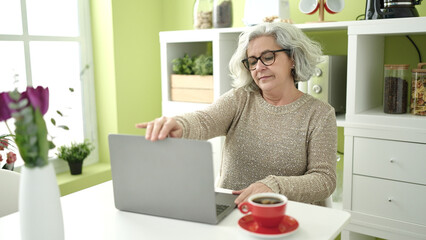 Sticker - Middle age woman with grey hair using laptop sitting on table at home