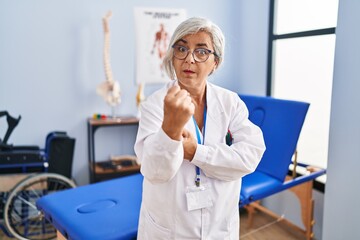 Sticker - Middle age woman with grey hair working at pain recovery clinic ready to fight with fist defense gesture, angry and upset face, afraid of problem