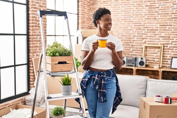 Wall Mural - African american woman smiling confident drinking coffee at new home