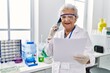© Krakenimages.com - Senior grey-haired woman wearing scientist uniform talking on the smartphone at laboratory