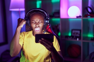 Canvas Print - African american woman playing video games with smartphone annoyed and frustrated shouting with anger, yelling crazy with anger and hand raised